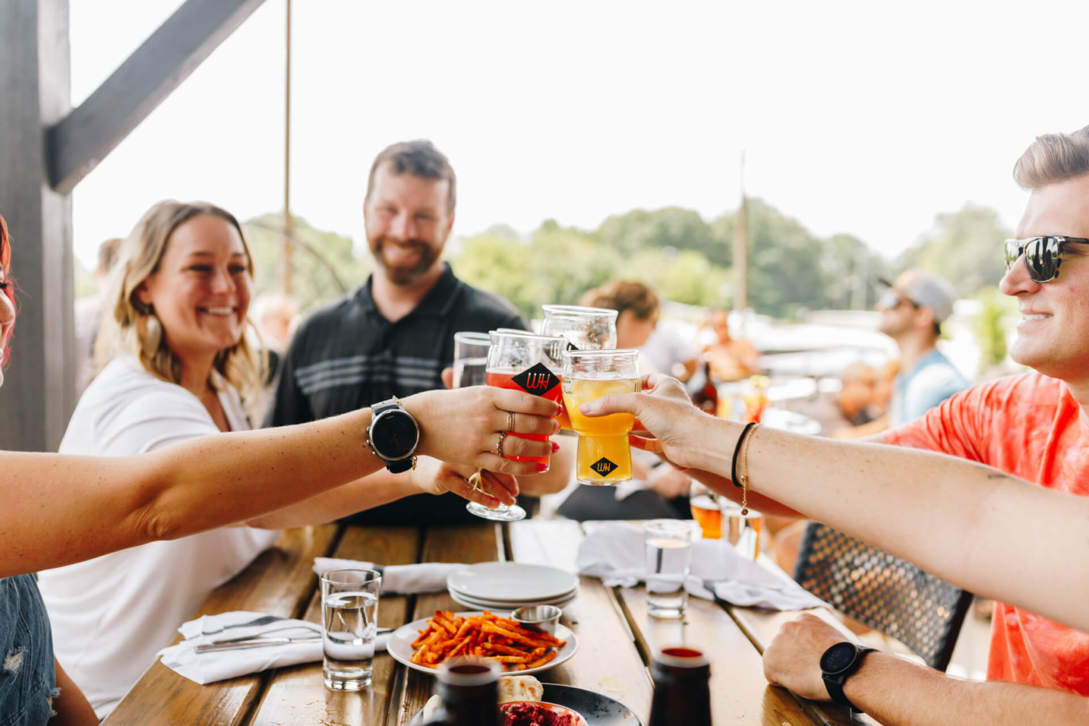 Friends cheersing their beers on the patio at Wye Hill Brewing in Downtown Raleigh