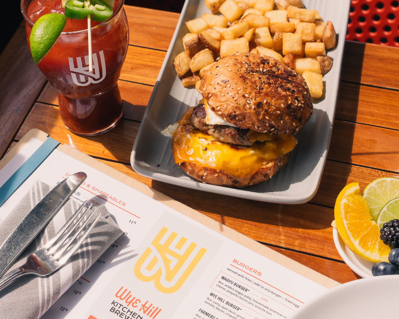 Wye Hill cheeseburger with home fries and a Bloody Mary garnished with jalapeno and lime on the sunny patio in downtown Raleigh